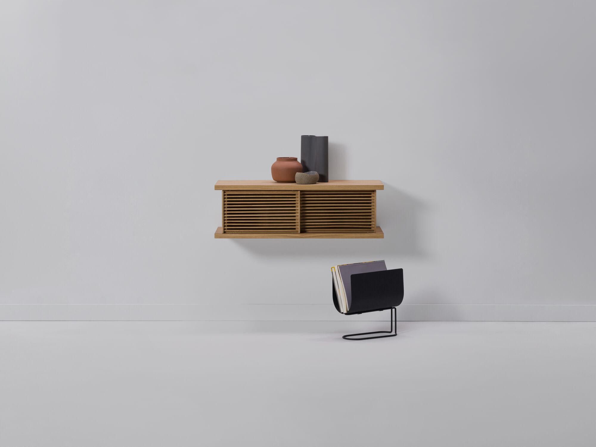 Small oak floating wall shelf with vases on it and magazine holder beside it